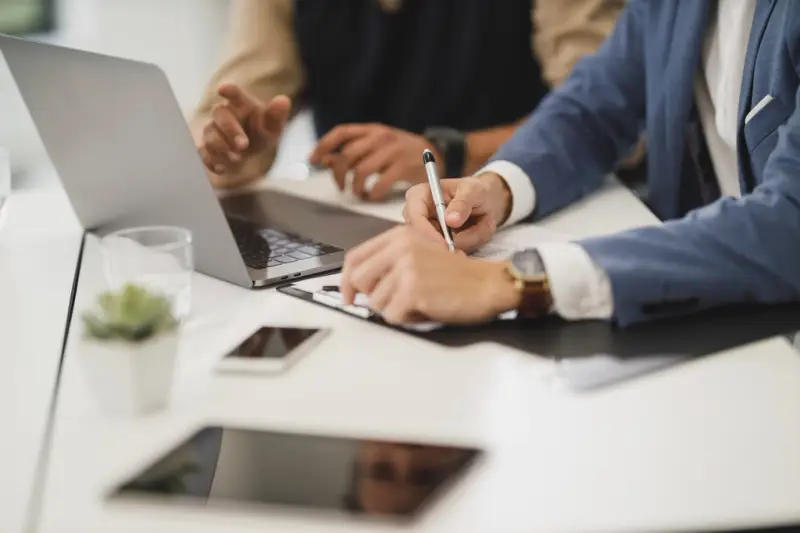 Dos personas trabajando con portátiles en la misma mesa
