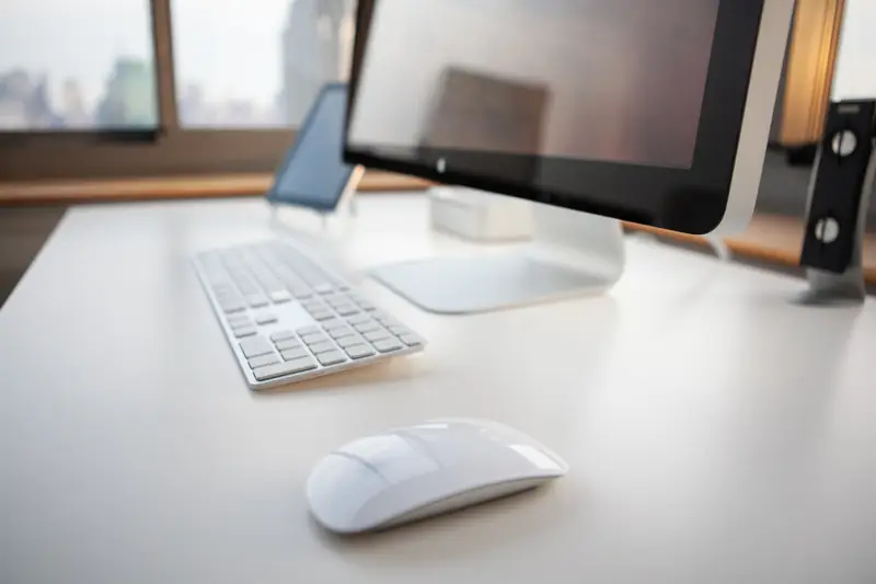 Monitor, teclado y ratón sobre una mesa blanca