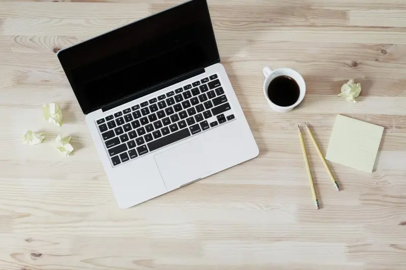 Portátil abierto sobre una mesa de madera clara con una taza de café