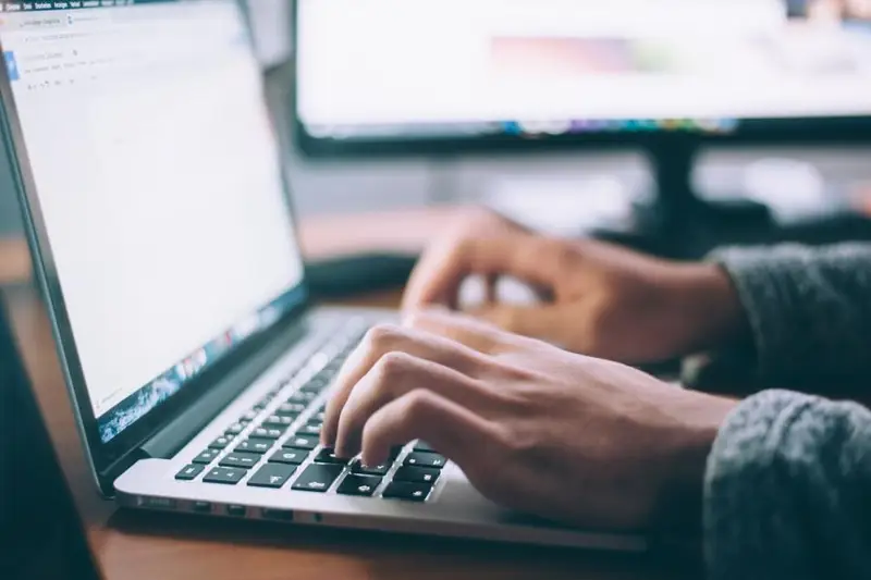 Manos escribiendo en el teclado de un portátil