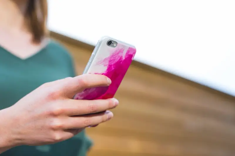 Mano sosteniendo un móvil con funda rosa