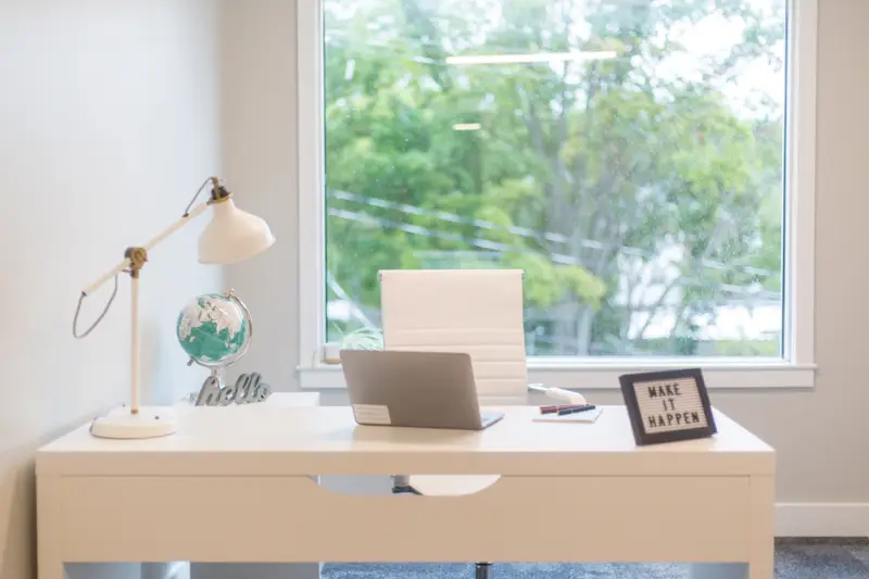 Portátil sobre un escritorio blanco junto a una ventana