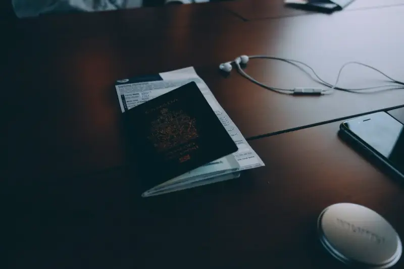 Pasaporte sobre una mesa oscura junto a unos auriculares