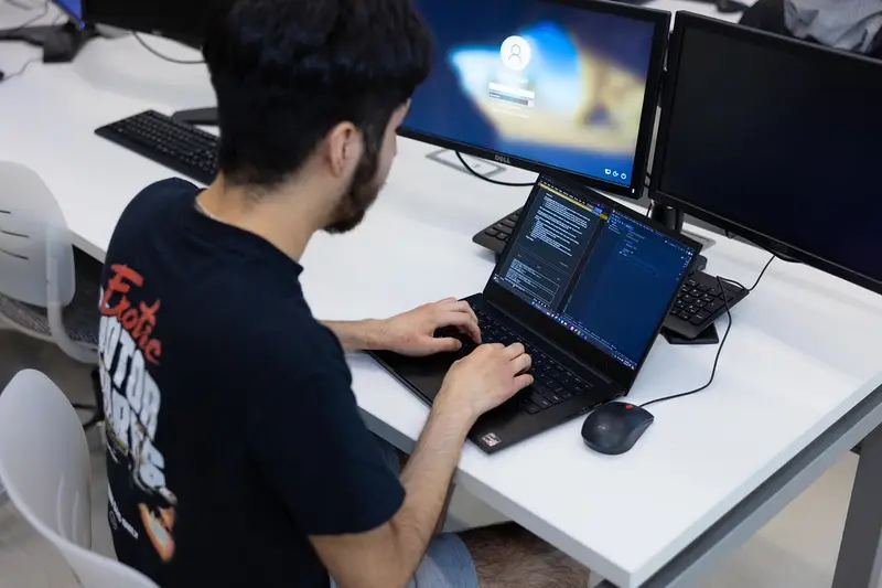 Estudiante programando en un portátil en un aula de ordenadores