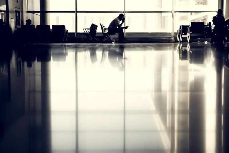 Persona con un portátil sentada en una terminal de aeropuerto