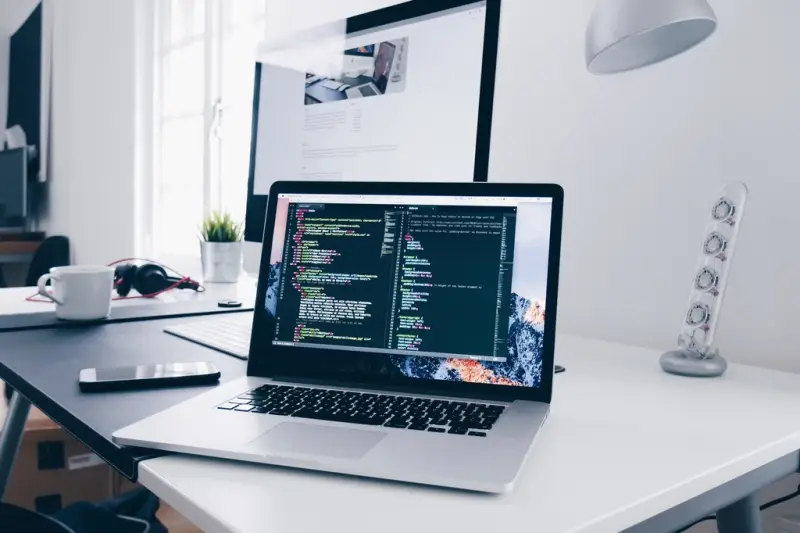Portátil con código de programación en pantalla sobre una mesa blanca