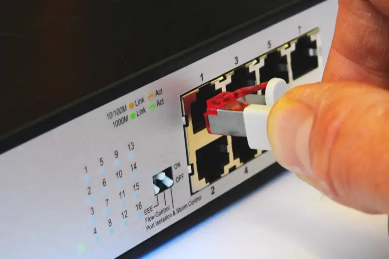 Mano conectando un cable de red a un conmutador