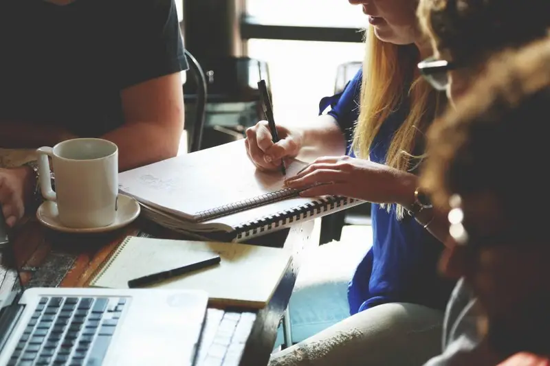 Reunión de trabajo con portátiles y cuadernos sobre una mesa