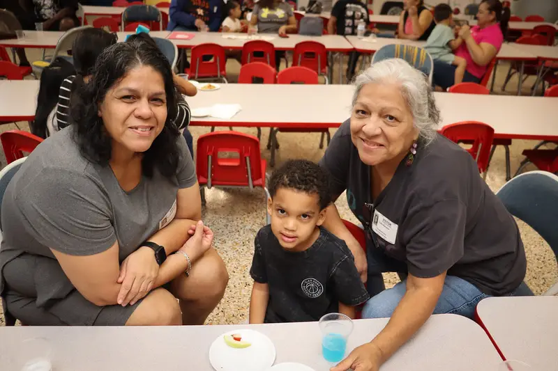 Dos mujeres y un niño sonriendo juntos en una sala