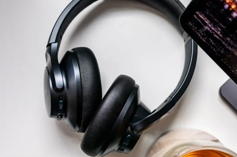 Auriculares inalámbricos negros junto a un móvil