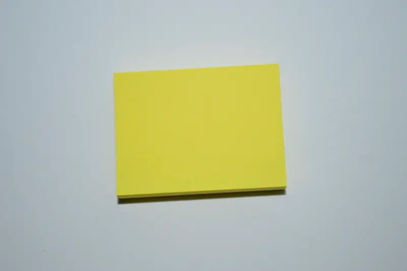 Nota adhesiva amarilla en blanco sobre fondo gris