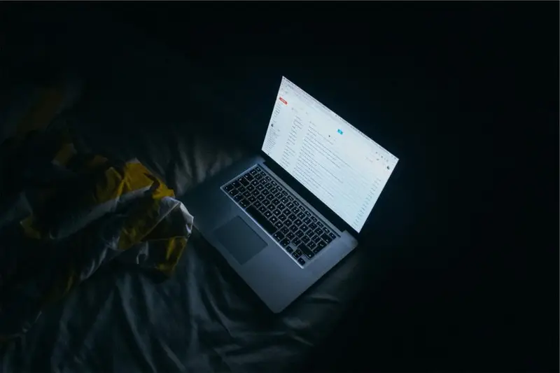 Portátil abierto con la pantalla tenue en una habitación oscura