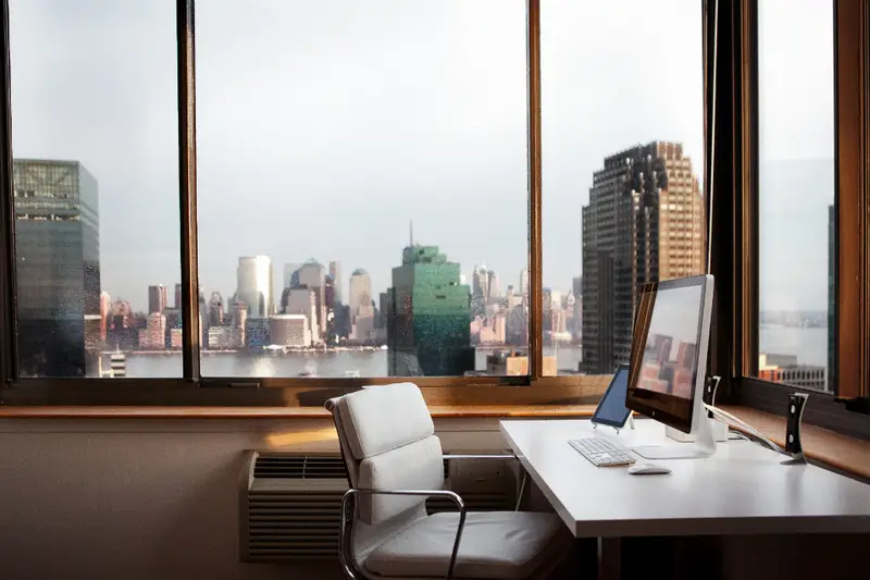 Escritorio con ordenador junto a un ventanal con vistas a la ciudad
